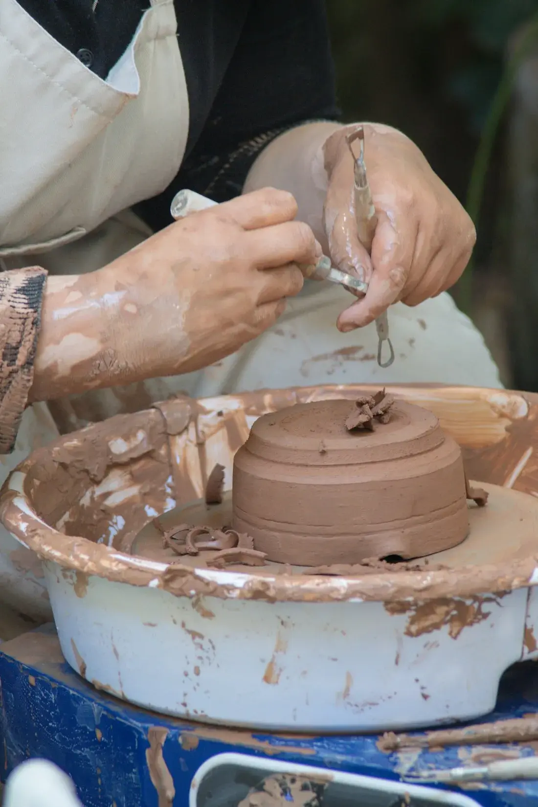 A potter’s hands trimming a clay bowl on a pottery wheel